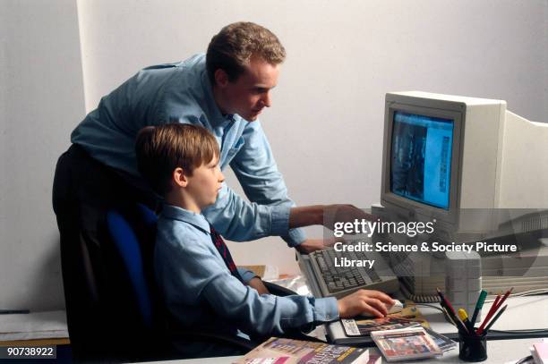 Gabriel Bailey, aged 11, seated at a PC to access an educational software package on a CDRom. He is using a mouse to navigate around the material on...