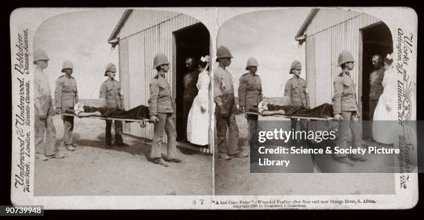 Wounded fusilier being carried on a stretcher to receive medical attention after a Boer raid near the Orange River. One of a boxed set of stereoscope...