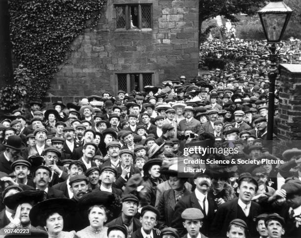 Crowd of people all looking skyward, c 1900s.