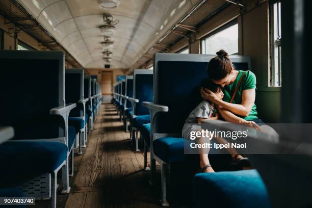 mother and child having intimate moment in train - familie in der bahn stock-fotos und bilder