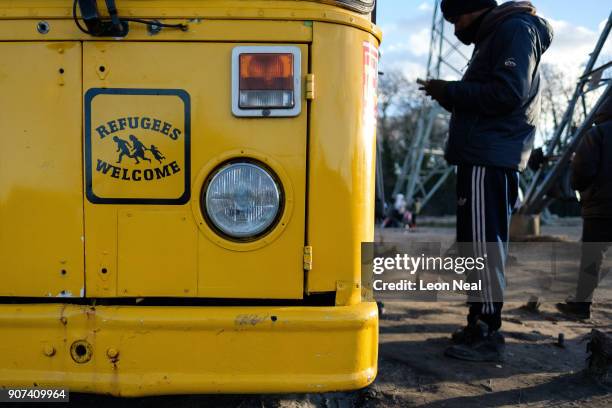 Young man uses the free wifi, provided by the "Help Refugees" charity, at a drop-in area on an industrial estate on January 19, 2018 in Calais,...