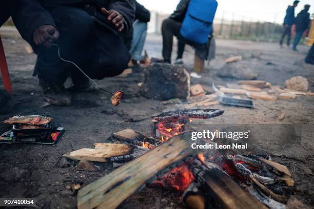 Migrant cooks some food on a campfire near an industrial estate on January 19, 2018 in Calais, France. During a visit to the UK by French President...