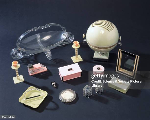 The acrylic objects include a pink table lighter, a powder compact, a photograph holder, candlesticks and a green bon-bon tray and two pepper pots in...