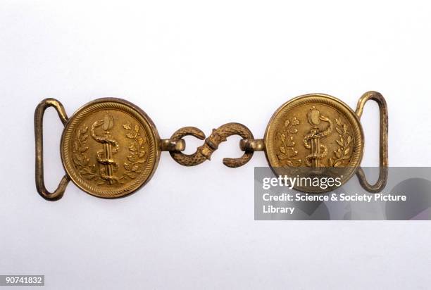 The buckle consists of two discs with an embossed caduceus and foliage, linked by a serpent made of ormolu. It is in the style worn by medical...