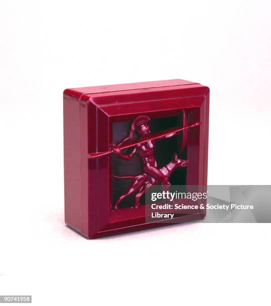The box is made of burgundy plastic and has a lid of open-work decoration showing a Greek warrior holding a spear and shield, accompanied by his...