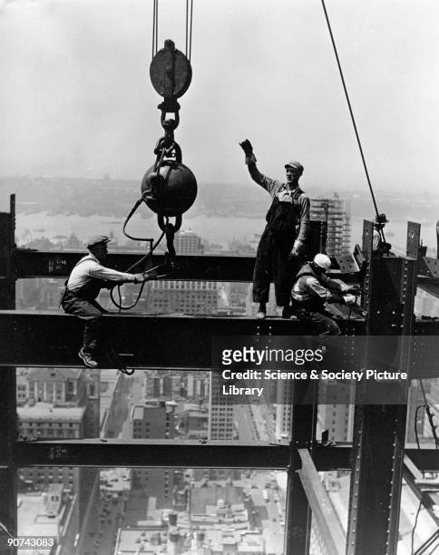 Photograph by Lewis Wickes Hine , showing members of a derrick gang fixing a beam during the construction of the Empire State Building, with the...