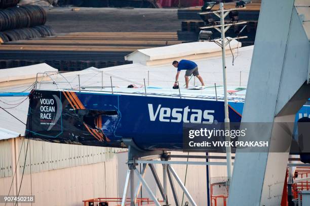 Crew member of the Vestas 11th Hour Racing team walks on their damaged yacht, as it sits in a dock for repairs after a collision with a fishing...