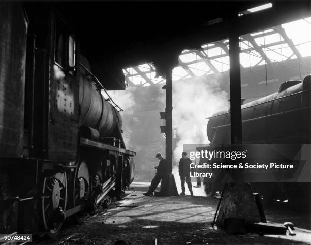 Grimy 8F and Class 5 steam locomotives in a run down shed, 1960s. Photograph by Bishop Eric Treacy. Treacy was often allowed special access to many...