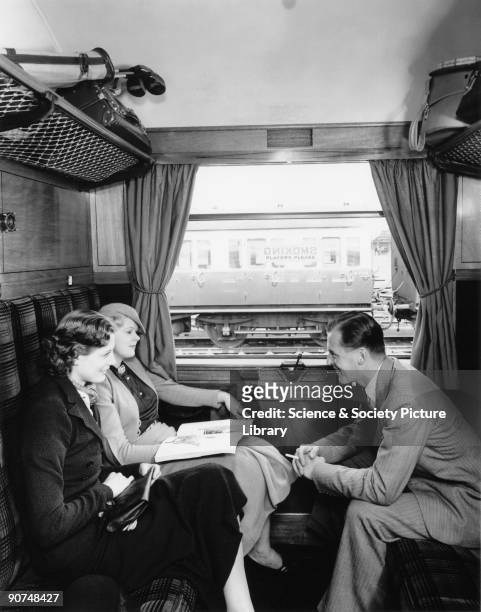 Models posing in the compartment of a railway carriage; preliminary photograph taken for a poster to advertise GWR's 'Cornish Riviera' service from...