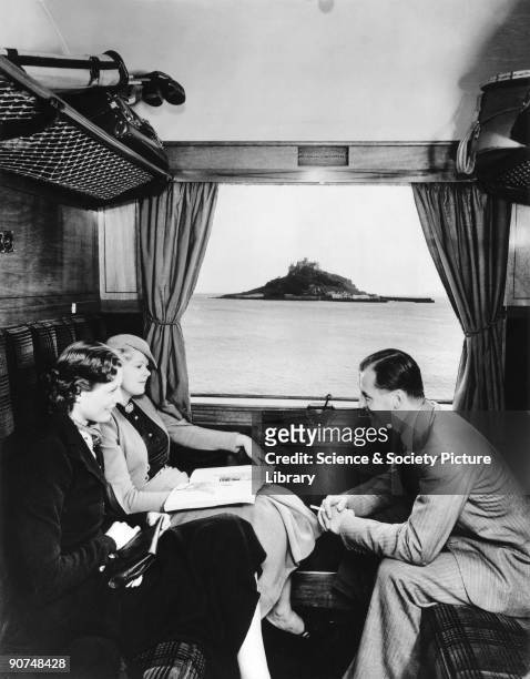 Models posing in the compartment of a railway carriage which was actually parked in a convenient siding. The original photograph showed a railway...