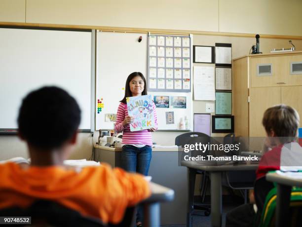young female student presenting work in classroom - kid presenting stockfoto's en -beelden