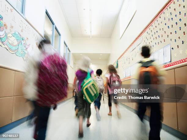 young students walking down hallway of school - on the move rear view stockfoto's en -beelden