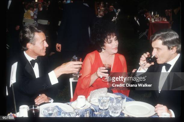 Fashion designer Halston, actress Elizabeth Taylor and her husband Senator John Warner sit at a party June, 1980 in Washington, DC. Taylor has...