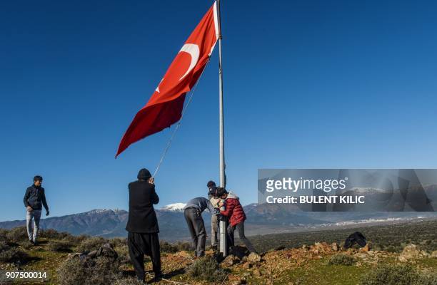 Villagers fix a broken Turkish flagpole near Syria border at Sugedik village, Hatay province, near the Syrian border, on January 20, 2018. / AFP...