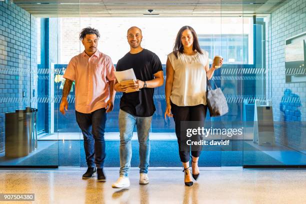 backlit business people walking through an office lobby - new zealand business stock pictures, royalty-free photos & images