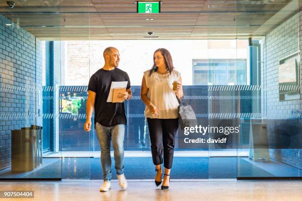 backlit business people walking through an office lobby - new zealand maori people talking stock pictures, royalty-free photos & images