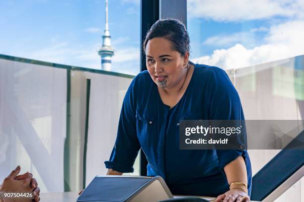 maorí empresaria hacer una llamada de conferencia con auckland skytower detrás - maorí fotografías e imágenes de stock