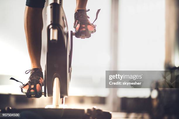 unrecognizable female athlete exercising on exercise bike in a gym. - cycling gym stock pictures, royalty-free photos & images