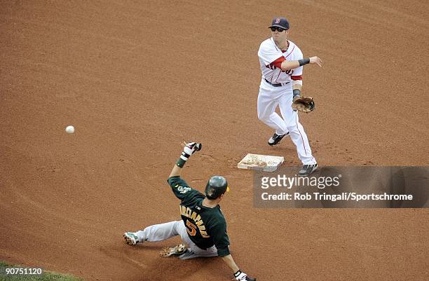 Dustin Pedroia of the Boston Red Sox throws to first over the sliding Nomar Garciaparra of the Oakland Athletics to complete a double play in a game...