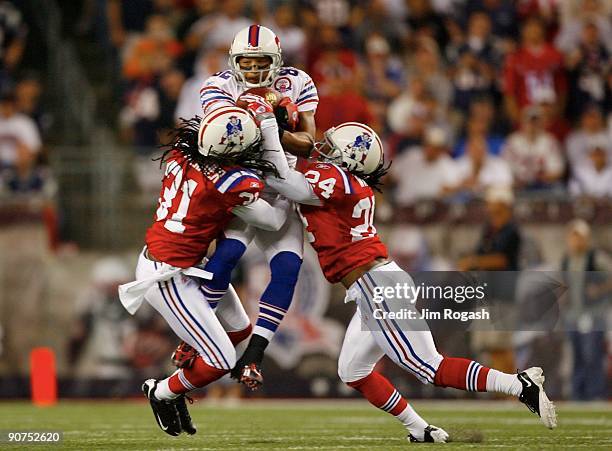 Wide receiver Josh Reed of the Buffalo Bills complete a pass between Brandon Meriweather and Jonathan Wilhite of the New England Patriots during the...