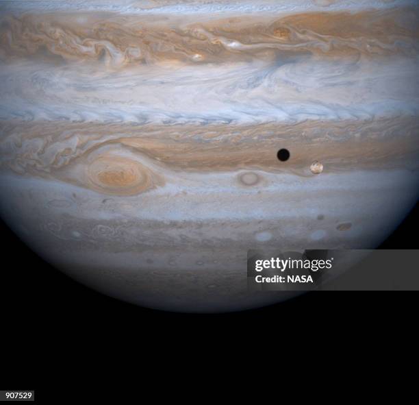 The entire body of Moon-sized Io, as it casts a black shadow, is captured here alongside the planet Jupiter in this picture taken by NASA's Cassini...