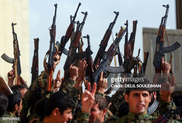 Syrian fighters hold up their weapons during their graduation ceremony near Syria's northeastern city of Hasakeh on January 20 at the end of a US-led...