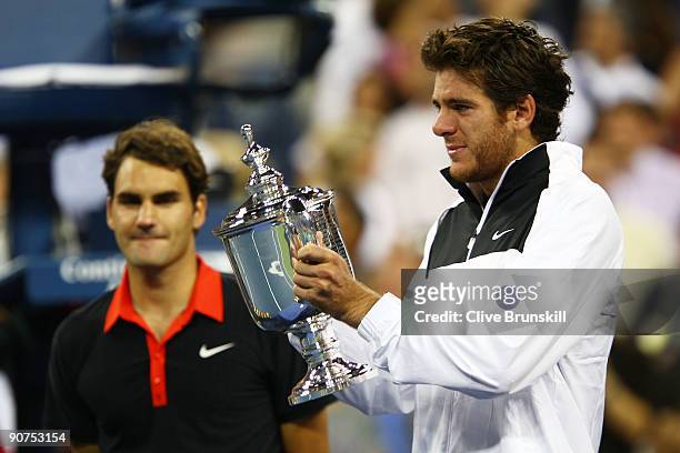 Juan Martin Del Potro of Argentina holds the championship trophy as Roger Federer of Switzerland looks on in the Men's Singles final on day fifteen...