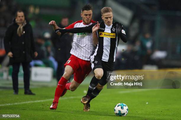 Jeffrey Gouweleeuw of Augsburg fights for the ball with Oscar Wendt of Moenchengladbach during the Bundesliga match between Borussia Moenchengladbach...