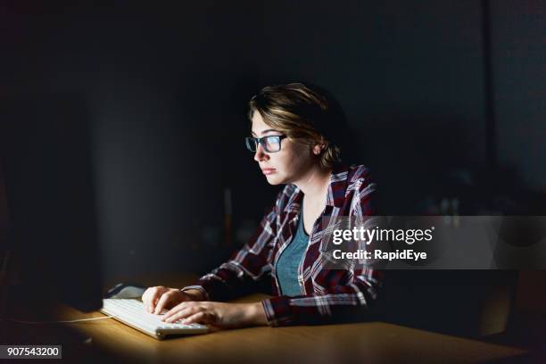 serious young woman working on computer late at night - staring at screen stock pictures, royalty-free photos & images