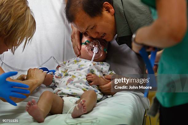 Lam Nguyen comforts his one-year-old son Dylan as a nurse inserts an IV drip into the child's arm in the emergency room of the non-profit Children's...