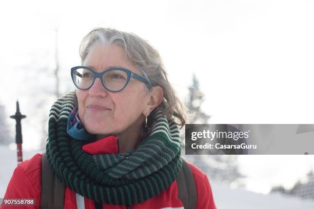 portrait of smiling reife frau wandern auf verschneiten berg - einzelne frau über 40 stock-fotos und bilder