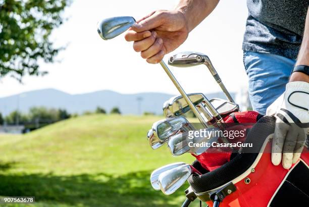 golfer pulling out a golf club from red golf bag - golf bag stock pictures, royalty-free photos & images
