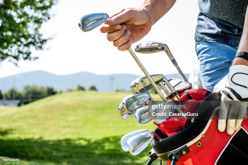 Golfista puxando para fora de um clube de golfe de saco de golfe vermelho