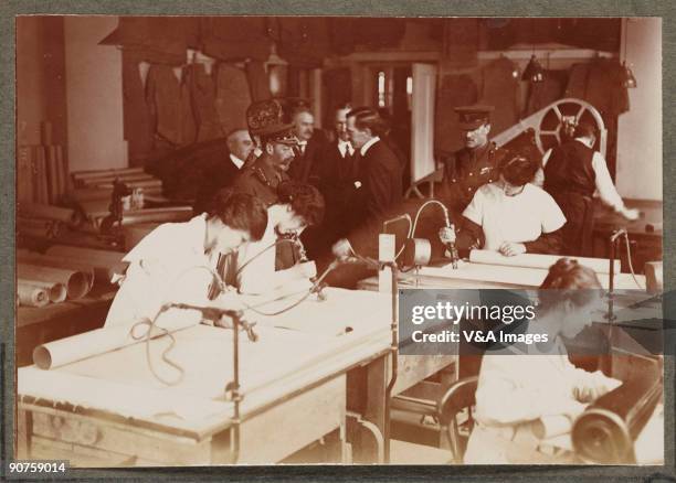 Printing out paper print. Photograph by Horace W Nicholls of the visit of King George V and Queen Mary to a factory manufacturing soldiers' uniforms....