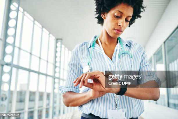 mujer médico comprobar su reloj de pulsera digital - puntualidad fotografías e imágenes de stock