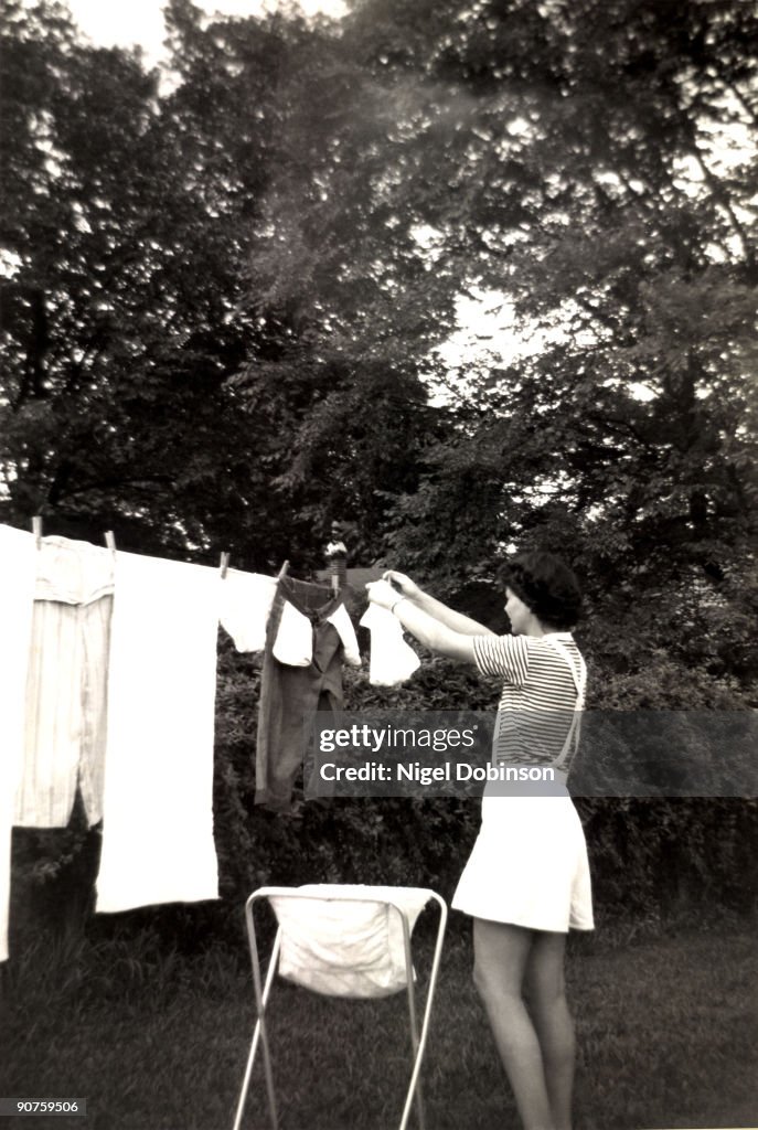 Woman hanging out washing, England, 1960s.