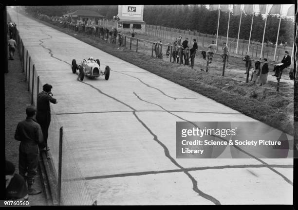 Photograph by Zoltan Glass. Spectators beside the track watch Stuck in his Auto-Union A-Type V16 at the back of the pits.