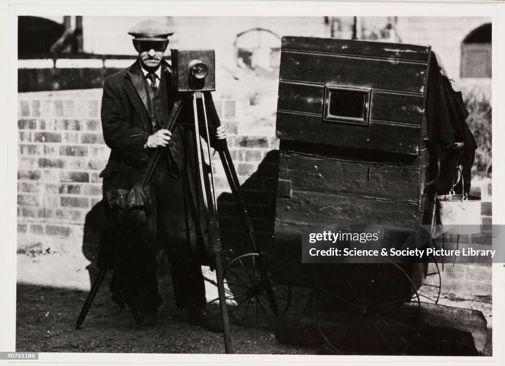 Photographer with tripod-mounted plate camera and other equipment, c 1890s.