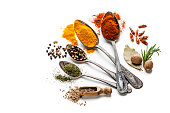 Spices and herbs in old spoons isolated on white background