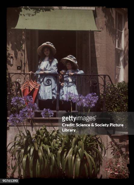 An autochrome of her daughters leaning on a balcony railing, taken by Etheldreda Janet Laing. The sunshine accentuates the bright colours of the...