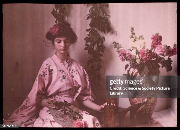 An autochrome portrait of her daughter dressed in a pink kimono, taken by Etheldreda Janet Laing. The design of the kimono is mirrored by the flower...