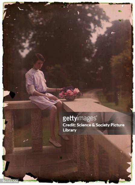 An autochrome of a young girl sitting on a balcony with a bowl of flowers, taken by Etheldreda Janet Laing in about 1910. The young girl is probably...