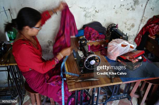 Nepalese woman working in a small business, sewing with an old singer machine.