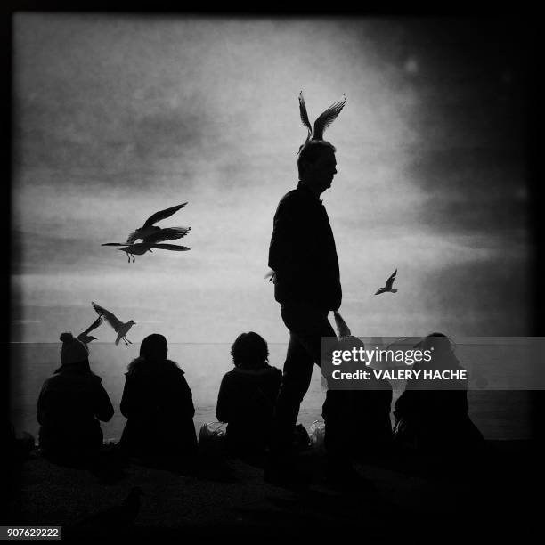 Picture taken with a mobilephone shows a man walks on the "promenade des Anglais" on the french riviera city of Nice on January 20, 2018. / AFP PHOTO...