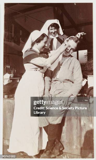 Snapshot photograph of a an nurse giving a British soldier a shave with a cut-throat razor, taken by an unknown photographer in about 1918....