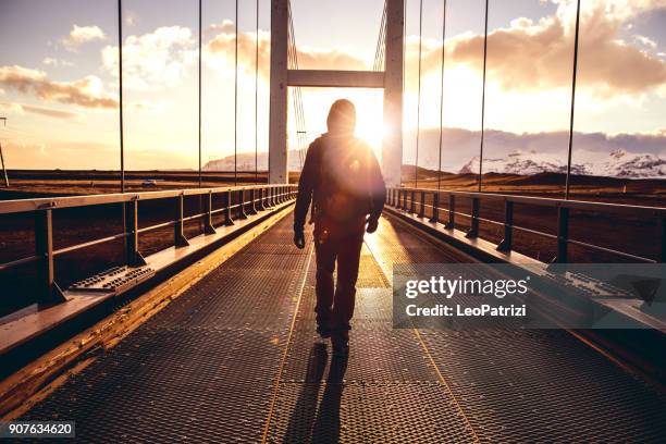 solo traveler walking on a bridge with arm raised - bridge stock pictures, royalty-free photos & images