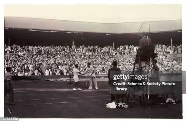 Snapshot photograph of two tennis players at Wimbledon, taken by an unknown photographer in 1936. Fred Perry is photographed here winning the Davis...