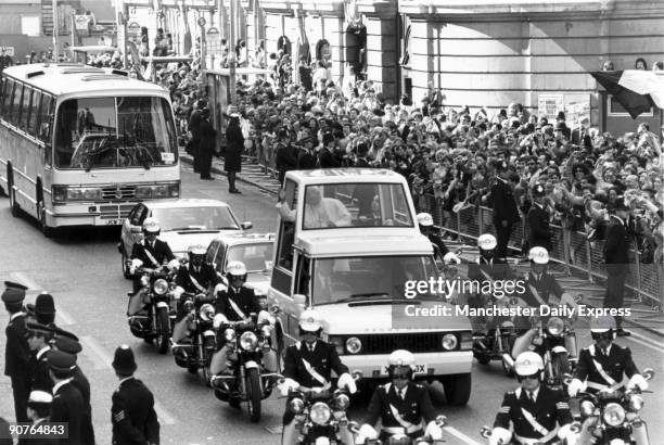 Police motorcyclists provide an escort for John Paul II in his �popemobile�, a specially adapted Range Rover, on the papal procession from Victoria...