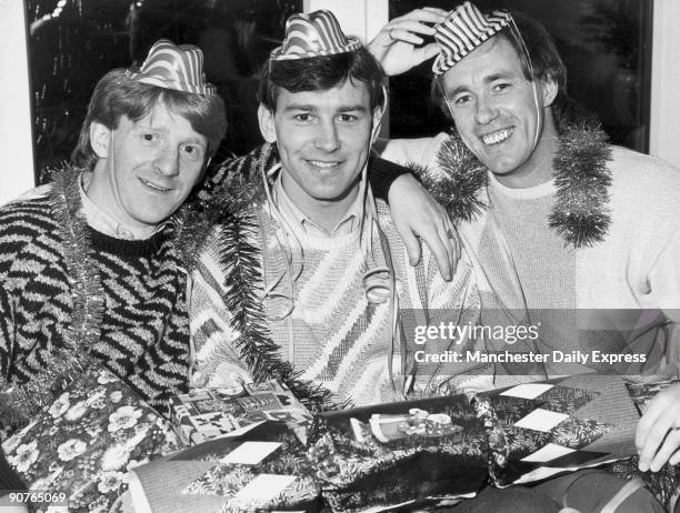 Manchester United players Gordon Strachan, Bryan Robson and Sammy McIlroy get into the Christmas spirit as they pose for a photograph with a giant...