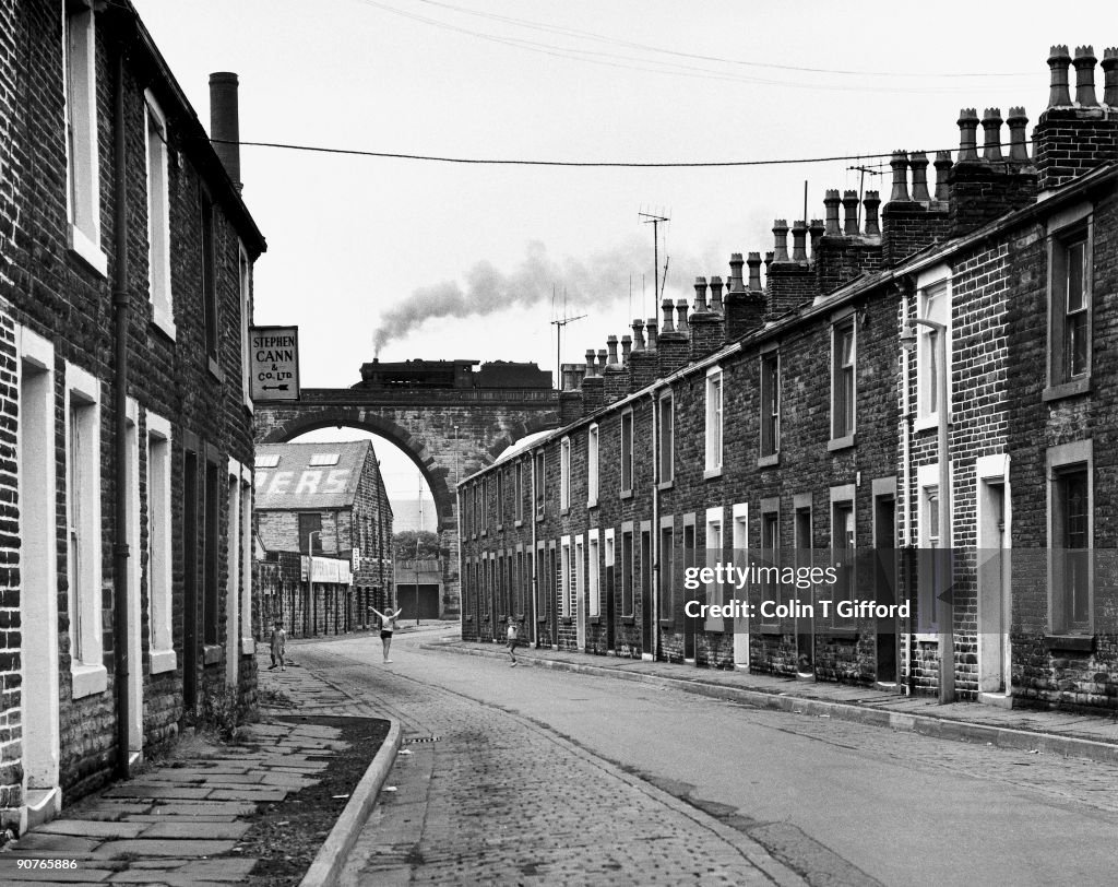 Steam train crossing a viaduct over a terraced street, Lancashire, 7 July 1968.